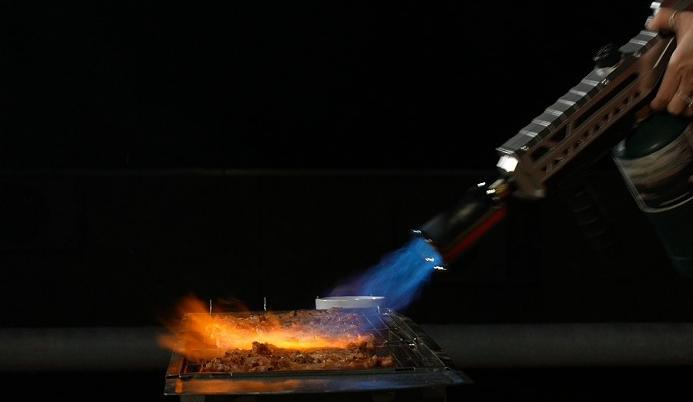 Gas torch lighting charcoal in a grill